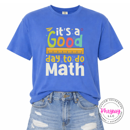 Mystic Blue Comfort Colors tee showing bright multicolor math teacher statement with ruler and colorful letter detail.