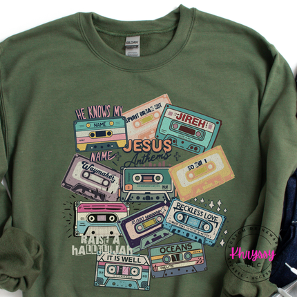 Military Green crewneck showing vintage Jesus Anthems cassette tapes.