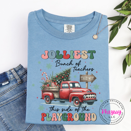 Flat lay of the Jolliest Teachers truck Christmas long sleeve tee in Ice Blue.