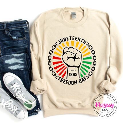 Sand crewneck sweatshirt displaying a black raised-fist Juneteenth 1865 graphic.