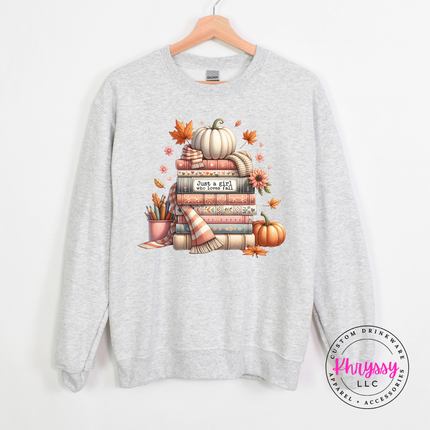 Woman wearing an Ash crewneck sweatshirt with a cozy book stack design.