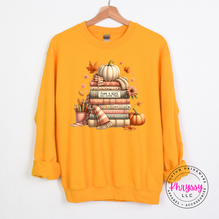 Gold crewneck sweatshirt with a bookish fall illustration and white pumpkin.