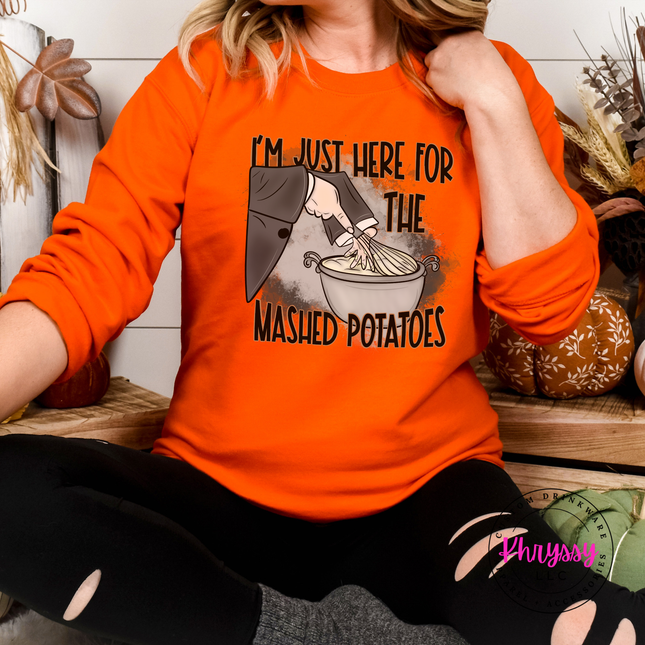 Woman wearing an orange crewneck sweatshirt with a mashed potatoes design.