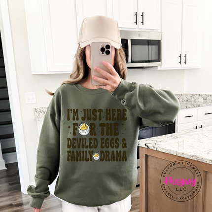 Woman wearing an Military Green crewneck sweatshirt with a deviled eggs family drama graphic.