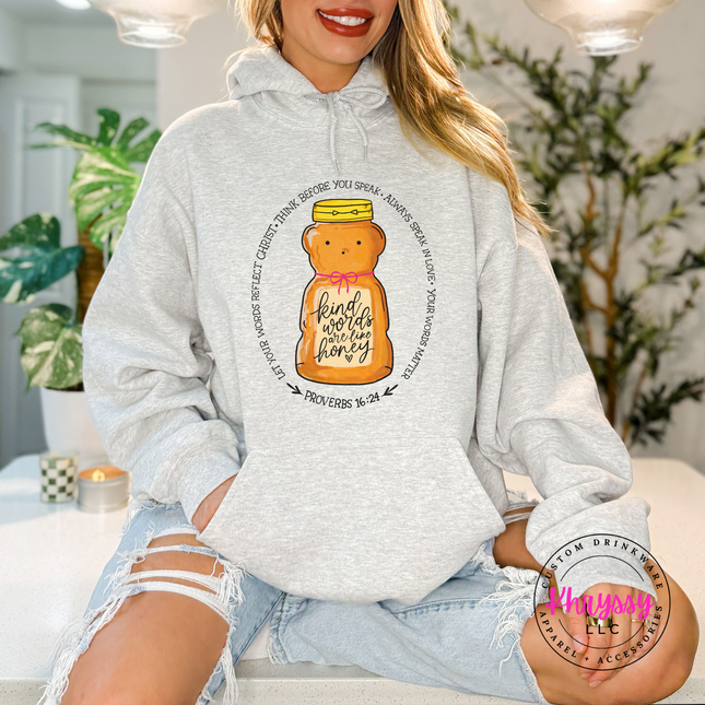 Person wearing a gray hoodie with a honey bear graphic and text, sitting in a home setting.