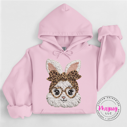 Pink hoodie with a bunny design wearing glasses and a leopard print headband on a light gray background.