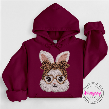 Maroon hoodie with a bunny design wearing glasses and a leopard print headband on a white background.