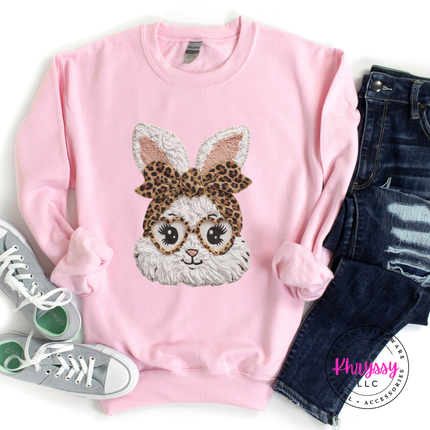 Pink sweatshirt with a rabbit design wearing a leopard print bow, paired with jeans and sneakers on a white background.