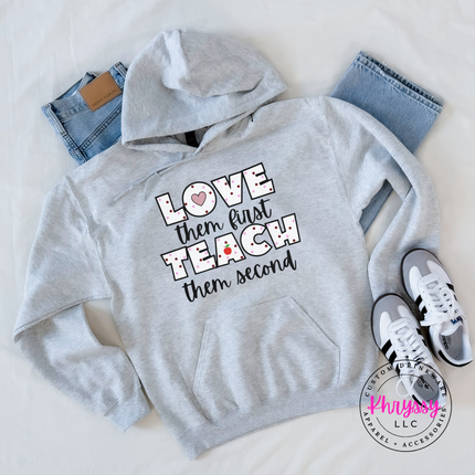 Clean ash Gildan hoodie featuring love them first teach them second black polka dot apple teacher statement