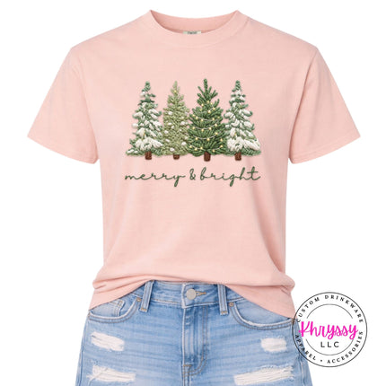 Close up of soft script lettering under Christmas trees on a Peachy Comfort Colors tee.
