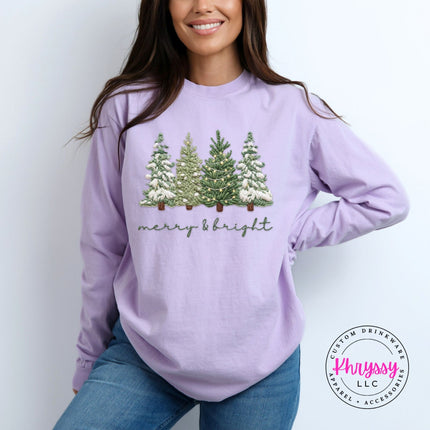 Orchid long sleeve tee showing four snowy evergreen trees above soft script lettering.