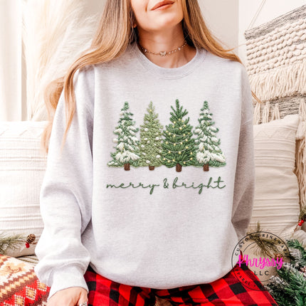 Ash crewneck sweatshirt with snowy evergreen trees and merry and bright script.