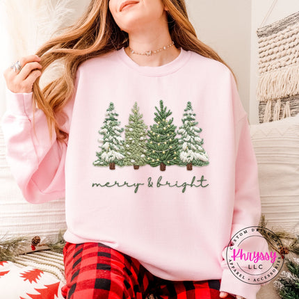 Light Pink crewneck sweatshirt showing four snowy evergreen trees above script lettering.