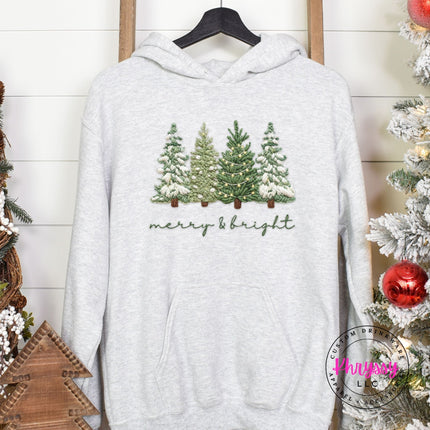 Ash pullover hoodie with snowy evergreen trees and merry and bright script.