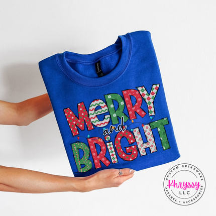 Close up of the Merry and Bright patterned art on a Royal crewneck sweatshirt.