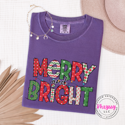 Flat lay of the Merry and Bright patterned Christmas tee in Grape.