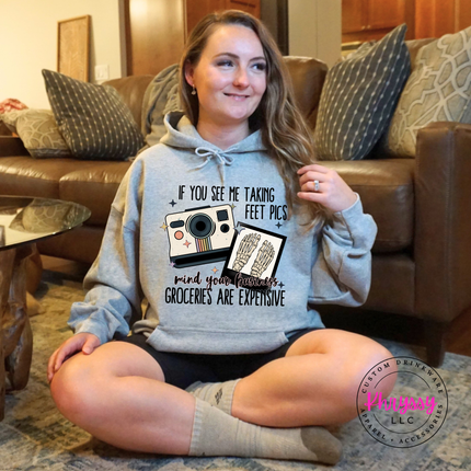 Person wearing a hoodie with a humorous graphic and text in a living room.