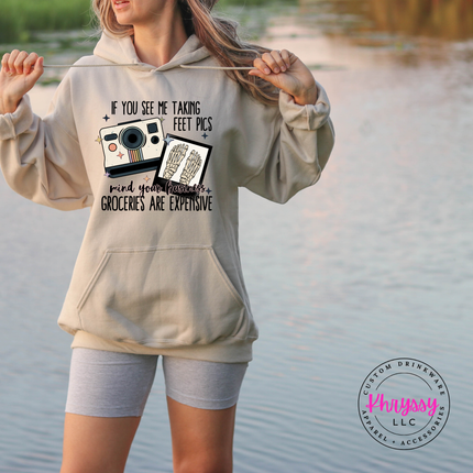 Person wearing a hoodie with a humorous graphic and text by a body of water.