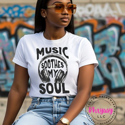 Woman wearing a white t-shirt with 'Music Soothes My Soul' design in front of graffiti.