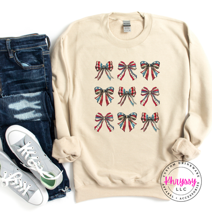 Sand crewneck sweatshirt displaying a patriotic coquette flag-bow graphic.