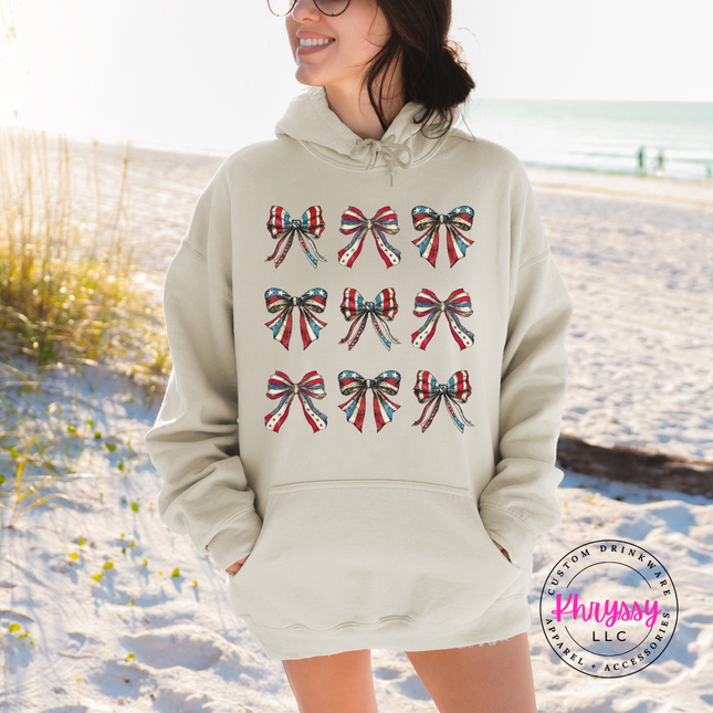 Sand crewneck sweatshirt displaying a patriotic coquette flag-bow graphic.