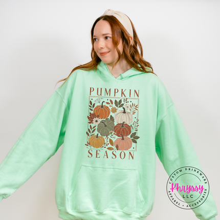 Woman wearing a mint pullover hoodie with a blush floral pumpkin design.