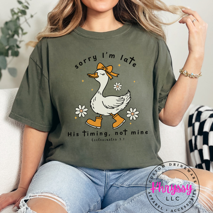 Person wearing a green t-shirt with a duck graphic and text, sitting on a couch.