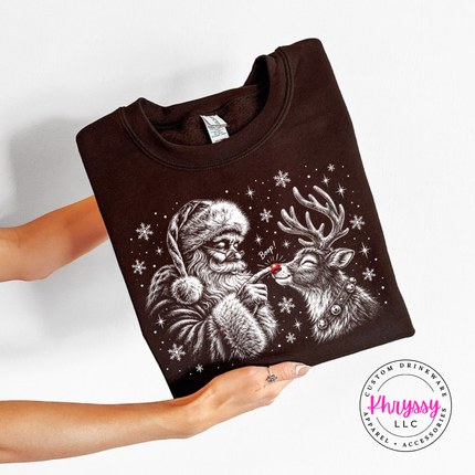 Santa giving his reindeer a nose boop on a Dark Chocolate crewneck sweatshirt.
