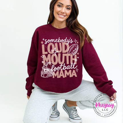 Woman wearing a Maroon crewneck sweatshirt with the loud mouth football mama graphic