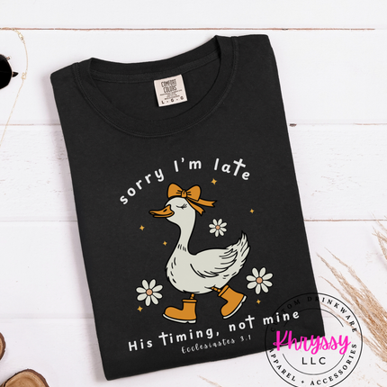 Black t-shirt with a graphic of a duck and text on a white wooden surface.