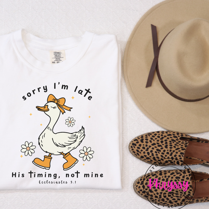 White t-shirt with a duck graphic and text, beige hat, and leopard print shoes on a white background