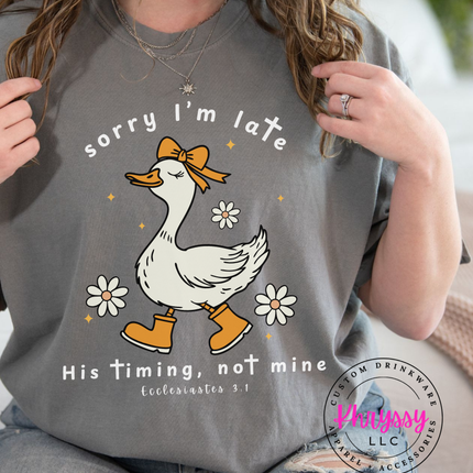 Person wearing a gray t-shirt with a duck graphic and text, holding the shirt open.