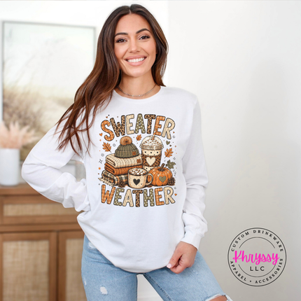 White long sleeve tee showing the sweater weather graphic with stacked books and pumpkins