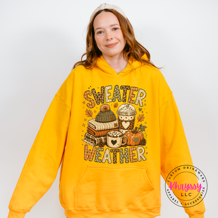 Woman wearing a Gold hoodie with the sweater weather fall graphic