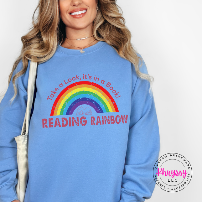 Carolina blue crewneck featuring a full rainbow and open book.