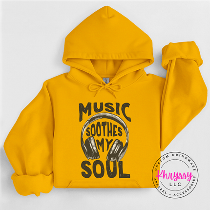 Yellow hoodie with 'Music Soothes My Soul' text and headphones graphic on a white background, featuring the brand 'Khryssy LLC'.