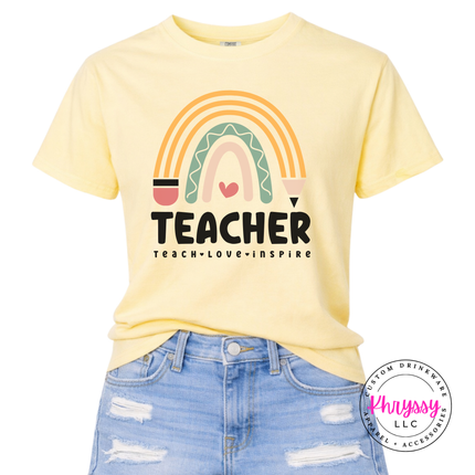 Close-up of pastel rainbow and pencil design on a Butter colored tee.