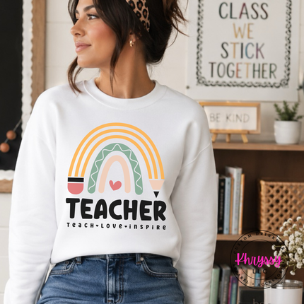 Teacher boho rainbow crewneck sweatshirt in White with teach love inspire text.