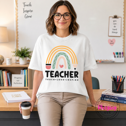 Woman wearing a White teacher boho rainbow tee with teach love inspire text.