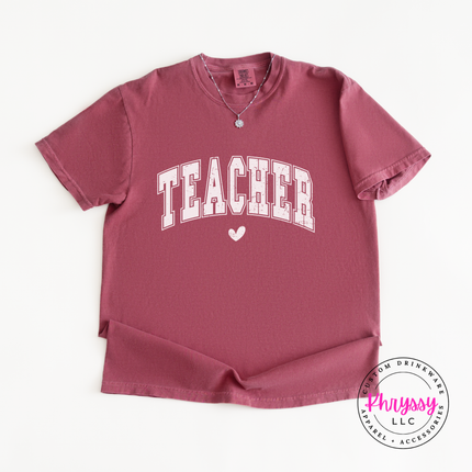 Close-up of arched teacher lettering and heart accent on a Brick colored tee.