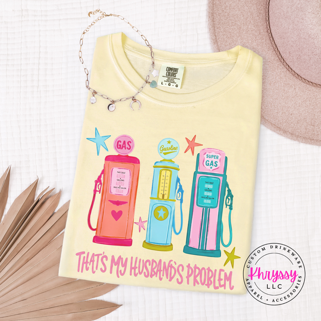 Folded yellow t-shirt with colorful gas pump design and text on a white surface.