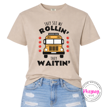 Sandstone tee with a playful school bus driver quote, folded flat lay.