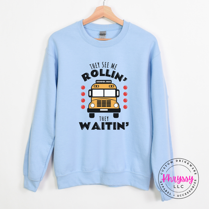 light blue crewneck sweatshirt with a school bus driver graphic.