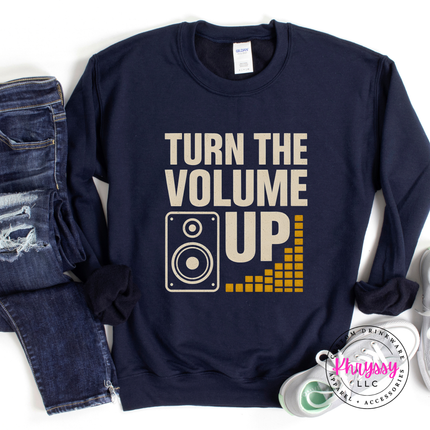 Navy blue sweatshirt with 'Turn the Volume Up' text and graphic, paired with jeans on a white background.