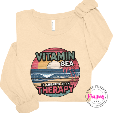 Soft cream tee showing a vintage Vitamin Sea coastal design.