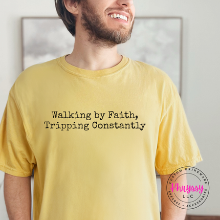 Man wearing a Mustard tee with the Walking By Faith, Tripping Constantly quote