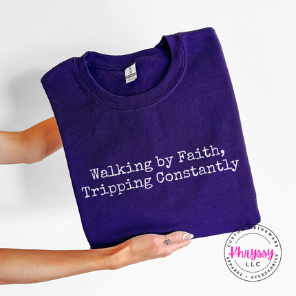 Purple crewneck sweatshirt with the Walking By Faith, Tripping Constantly quote