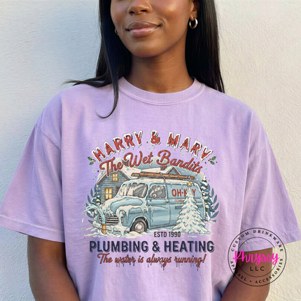 Orchid Comfort Colors tee showing a vintage plumbing and heating Christmas graphic, flat lay view.