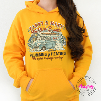 Gold hoodie styled with joggers, showing the full retro Christmas plumbing badge.